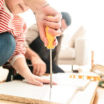 明るい室内で家具の組み立て作業を行う手元。ドライバーを使って丁寧にネジを締めている様子