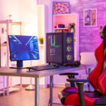 赤と黒のゲーミングチェアとLEDライトが映えるデスクトップPCのセットアップ